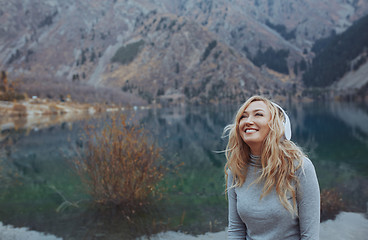 Image showing Woman wearing wireless headphones at the mountain lake