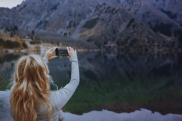 Image showing Woman making mobile photo at the mountain lake