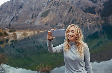 Image showing Smiling woman makes selfie at the mountain lake