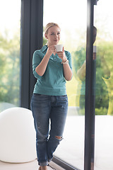 Image showing young woman drinking morning coffee by the window