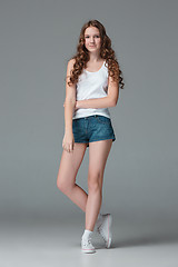 Image showing Full length of young slim female girl in denim shorts on gray background