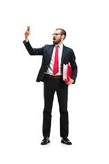 Image showing Angry businessman talking on the phone isolated over white background in studio shooting