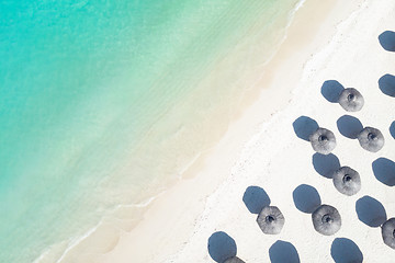 Image showing Aerial view of amazing tropical white sandy beach with palm leaves umbrellas and turquoise sea.