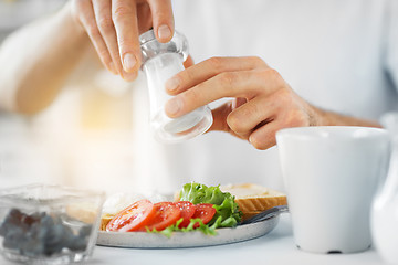 Image showing close up of male hands seasoning food by salt mill