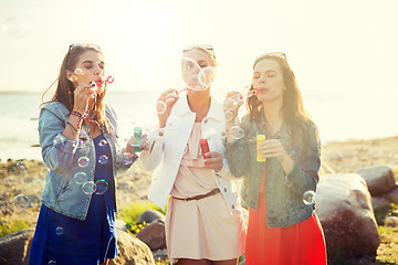 Image showing young women or girls blowing bubbles on beach