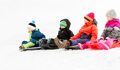 Image showing happy little kids sliding on sleds in winter