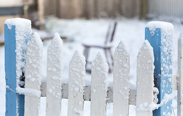 Image showing Snow covered picket fence in light falling snow