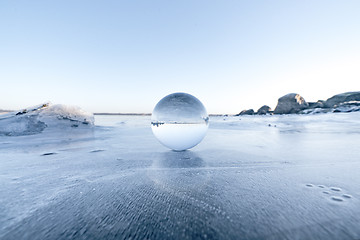 Image showing Elegant glass orb on ice on a frozen lake