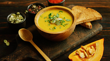 Image showing Fresh pumpkin soup in bowl on chopping board