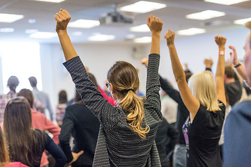 Image showing Participants of interactive motivational speech feeling empowered and motivated, hands raised high in the air.