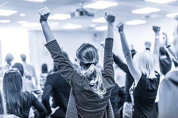Image showing Participants of interactive motivational speech feeling empowered and motivated, hands raised high in the air.