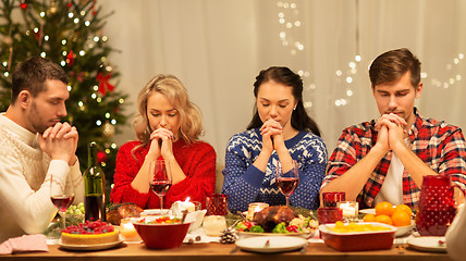 Image showing friends praying before christmas dinner at home 