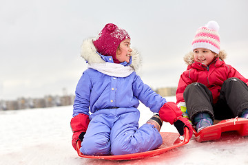 Image showing happy little girls on sleds outdoors in winter