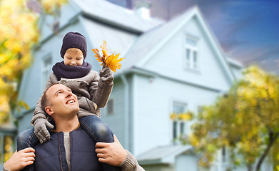 Image showing father and son with autumn maple leaves over house