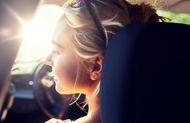 Image showing happy teenage girl or young woman in car