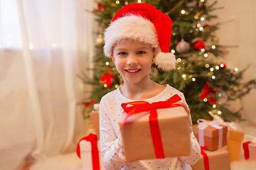 Image showing smiling girl in santa hat with christmas gift