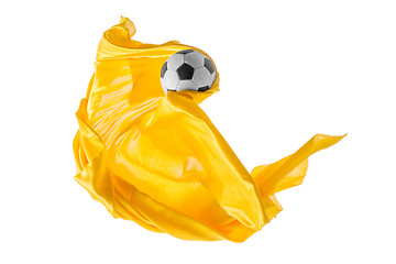 Image showing Soccer ball and Smooth elegant transparent yellow cloth isolated or separated on white studio background.