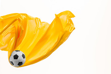 Image showing Soccer ball and Smooth elegant transparent yellow cloth isolated or separated on white studio background.