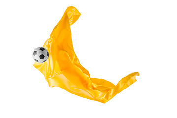 Image showing Soccer ball and Smooth elegant transparent yellow cloth isolated or separated on white studio background.