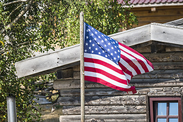 Image showing The flag of USA outside a wooden cabin