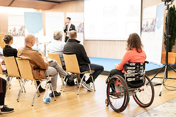 Image showing Rear view of nrecognizable woman on a wheelchair participating at business conference talk.