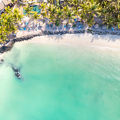 Image showing Aerial view of amazing tropical white sandy beach with palm leaves umbrellas and turquoise sea, Mauritius.