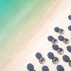 Image showing Aerial view of amazing tropical white sandy beach with palm leaves umbrellas and turquoise sea.