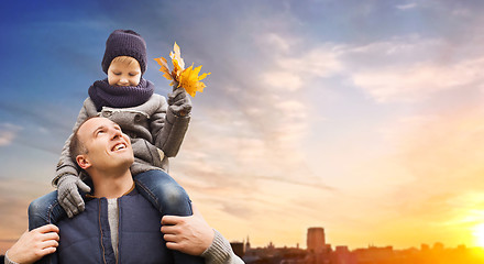 Image showing father carrying son with autumn leaves in city