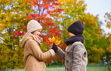 Image showing kids with autumn maple leaves over park background