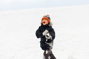 Image showing happy little boy playing with snow in winter