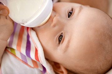 Image showing close up of baby sucking milk formula from bottle