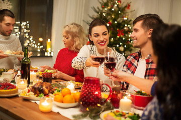 Image showing happy friends drinking red wine at christmas party