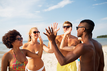 Image showing happy friends making high five on summer beach