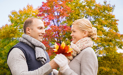 Image showing smiling couple with maple leaves in autumn park