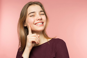 Image showing Woman smiling with perfect smile and white teeth on the pink studio background and looking at camera