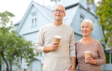 Image showing happy senior couple with coffee over living house