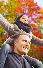Image showing happy father carrying son over autumn park 