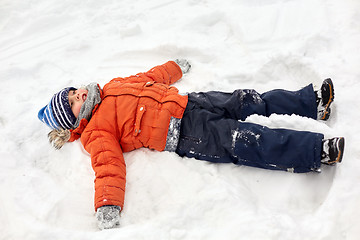 Image showing happy little boy making snow angels in winter