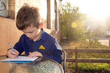 Image showing Boy doing homework outdoors