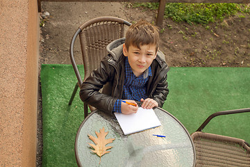 Image showing Boy is doing homework outdoors