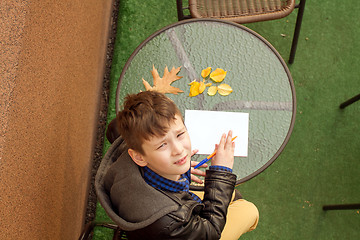 Image showing Boy is doing homework outdoors