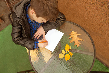 Image showing Boy is doing homework outdoors