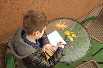 Image showing Boy is doing homework outdoors