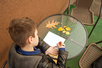 Image showing Boy is doing homework outdoors