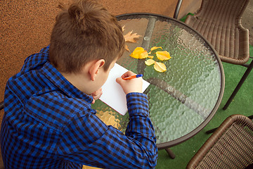 Image showing Boy is doing homework outdoors