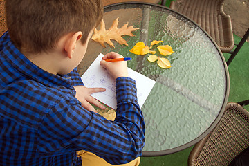 Image showing Boy is doing homework outdoors