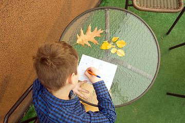 Image showing Boy is doing homework outdoors