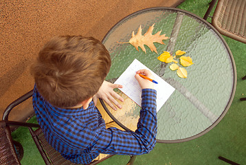 Image showing Boy is doing homework outdoors