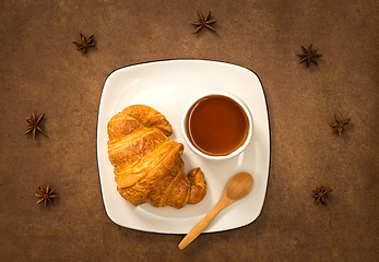 Image showing Croissant and cup of tea on brown leather background