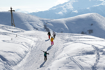 Image showing Skiers and snowboarders on snow road at sun winter morning